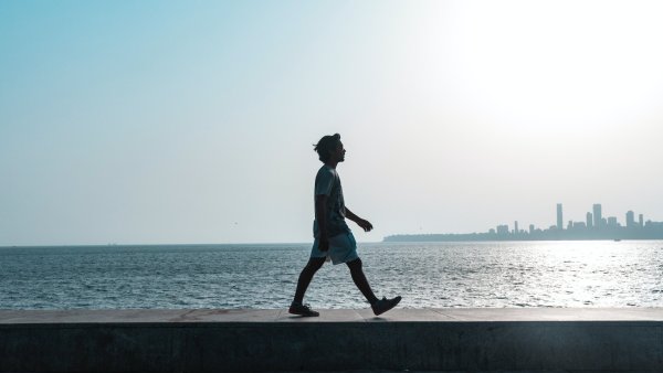 Image of a man walking along the beach in the sunlight