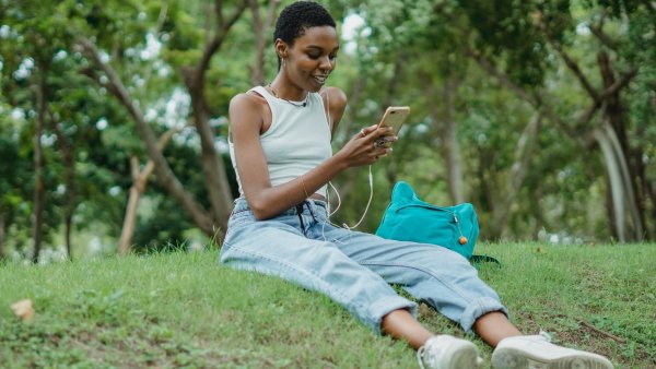 Girl sitting on a grassy hill texting her friends